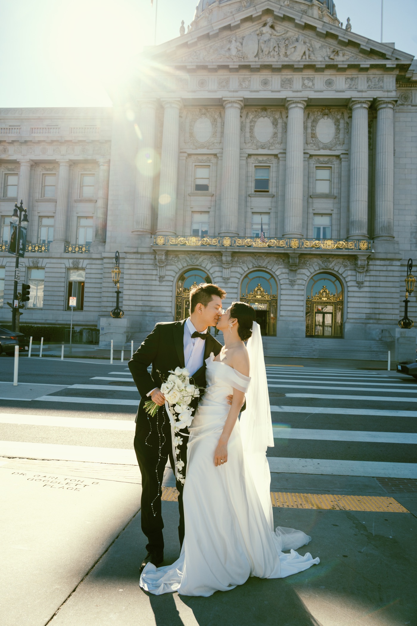 Newlyweds kissing in the sunlight outside San Francisco City Hall