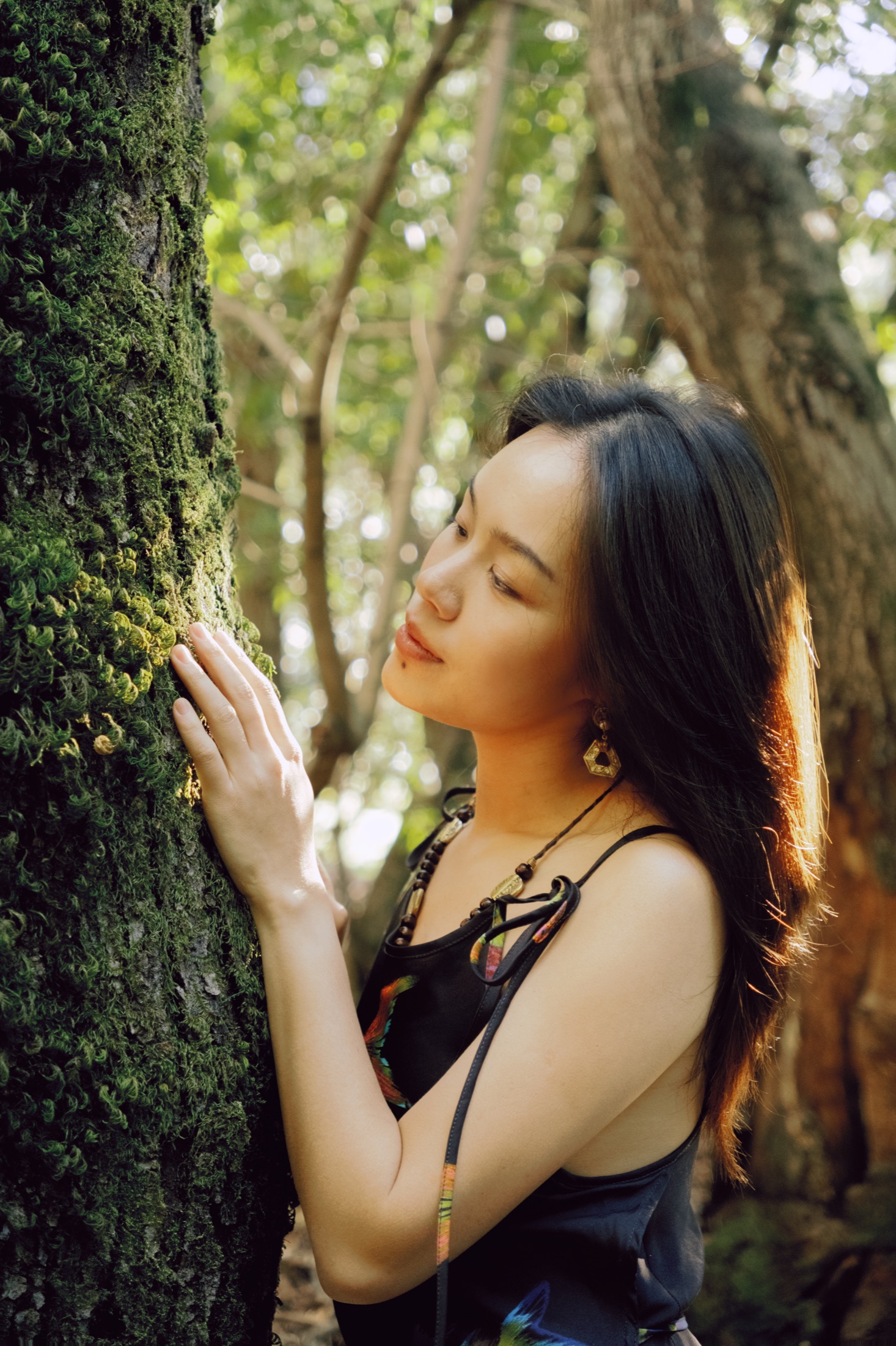 A quiet portrait of a woman beside a moss-covered tree