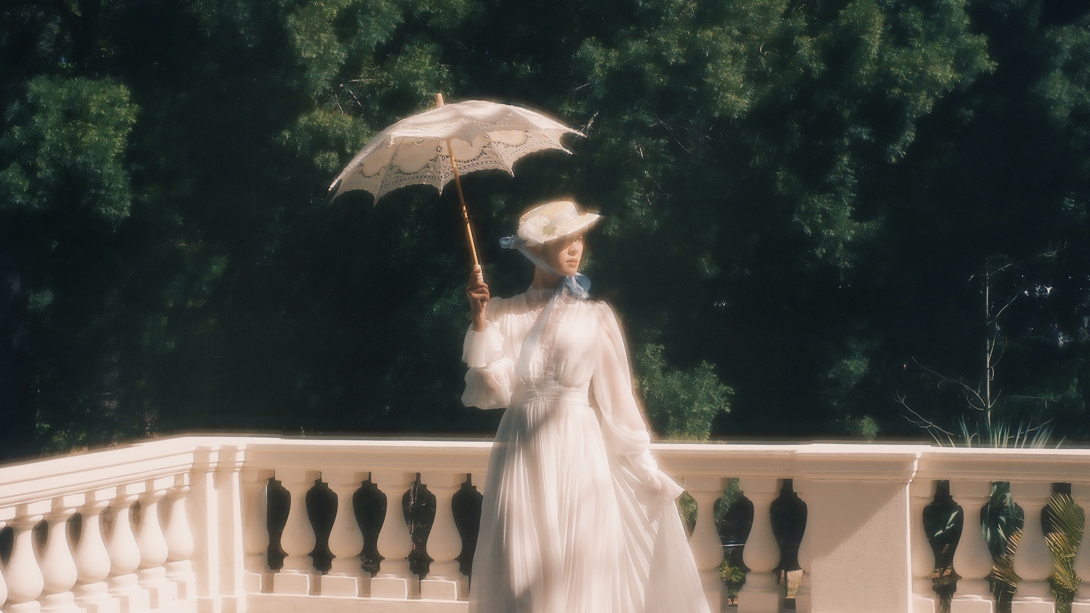 A woman in white holding a parasol in a dark landscape