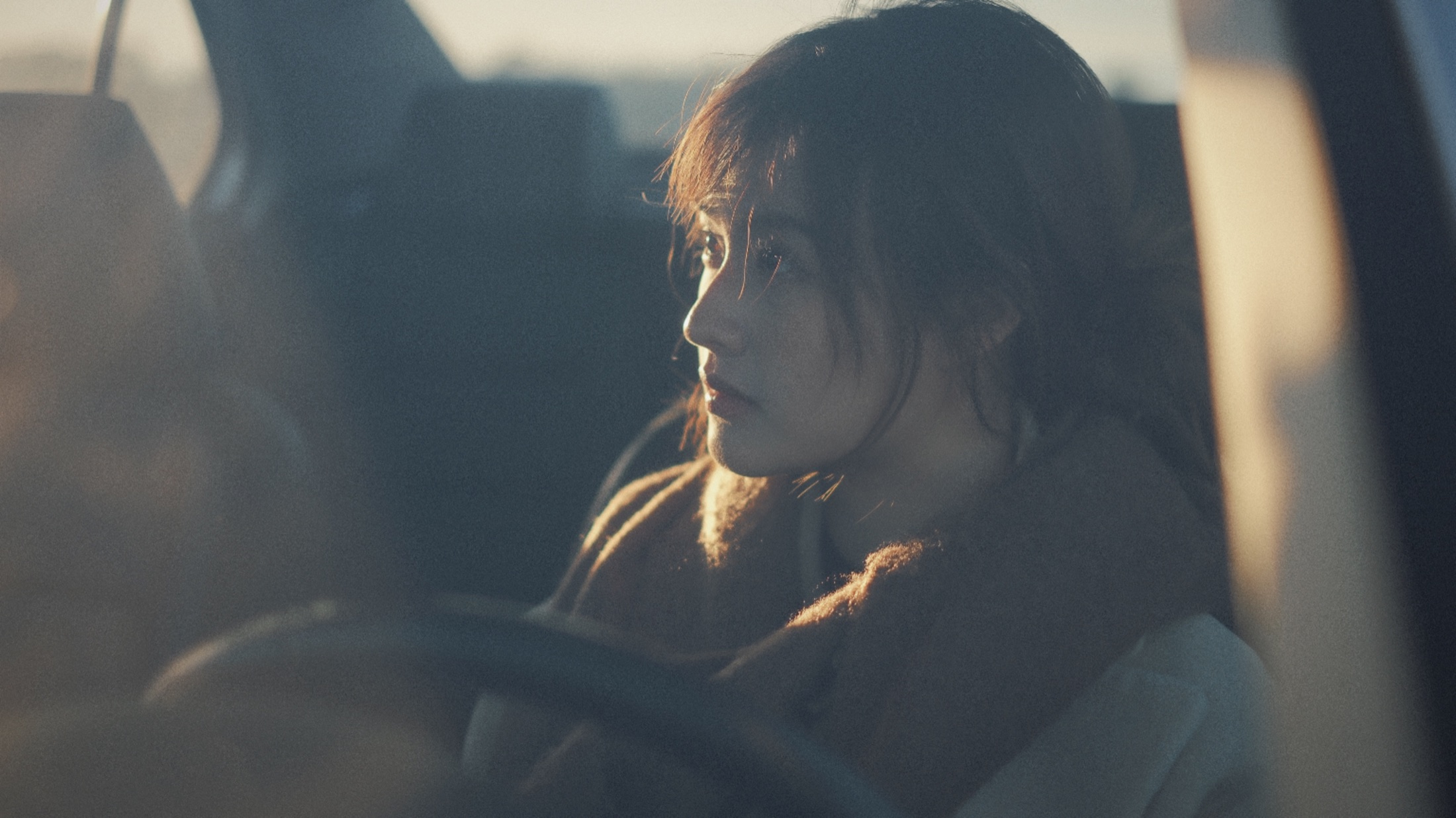 A cinematic portrait beside a car in warm evening light