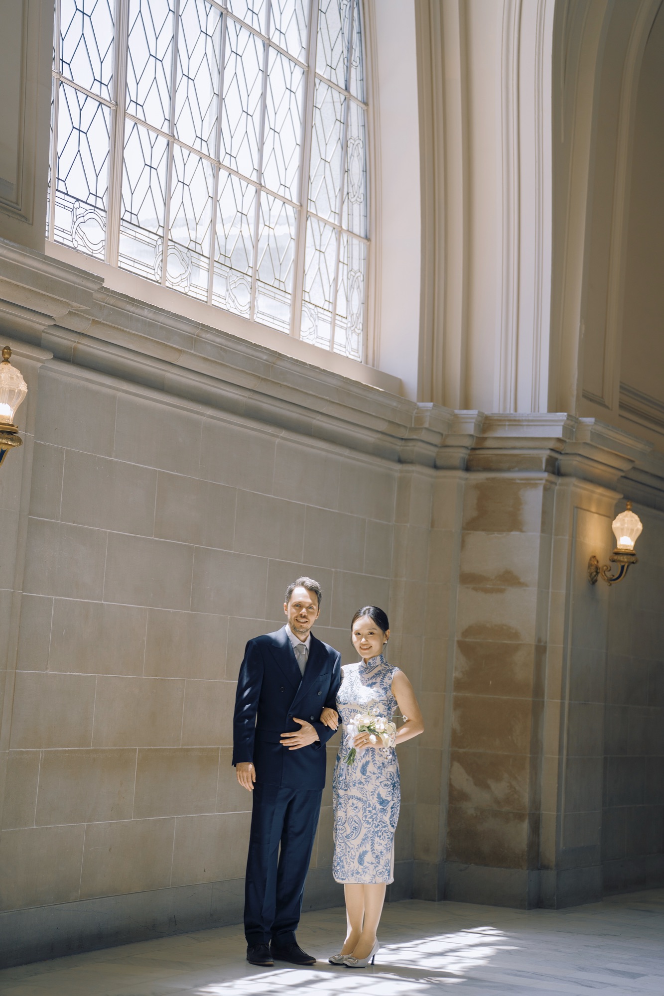 The couple framed by a tall window inside San Francisco City Hall