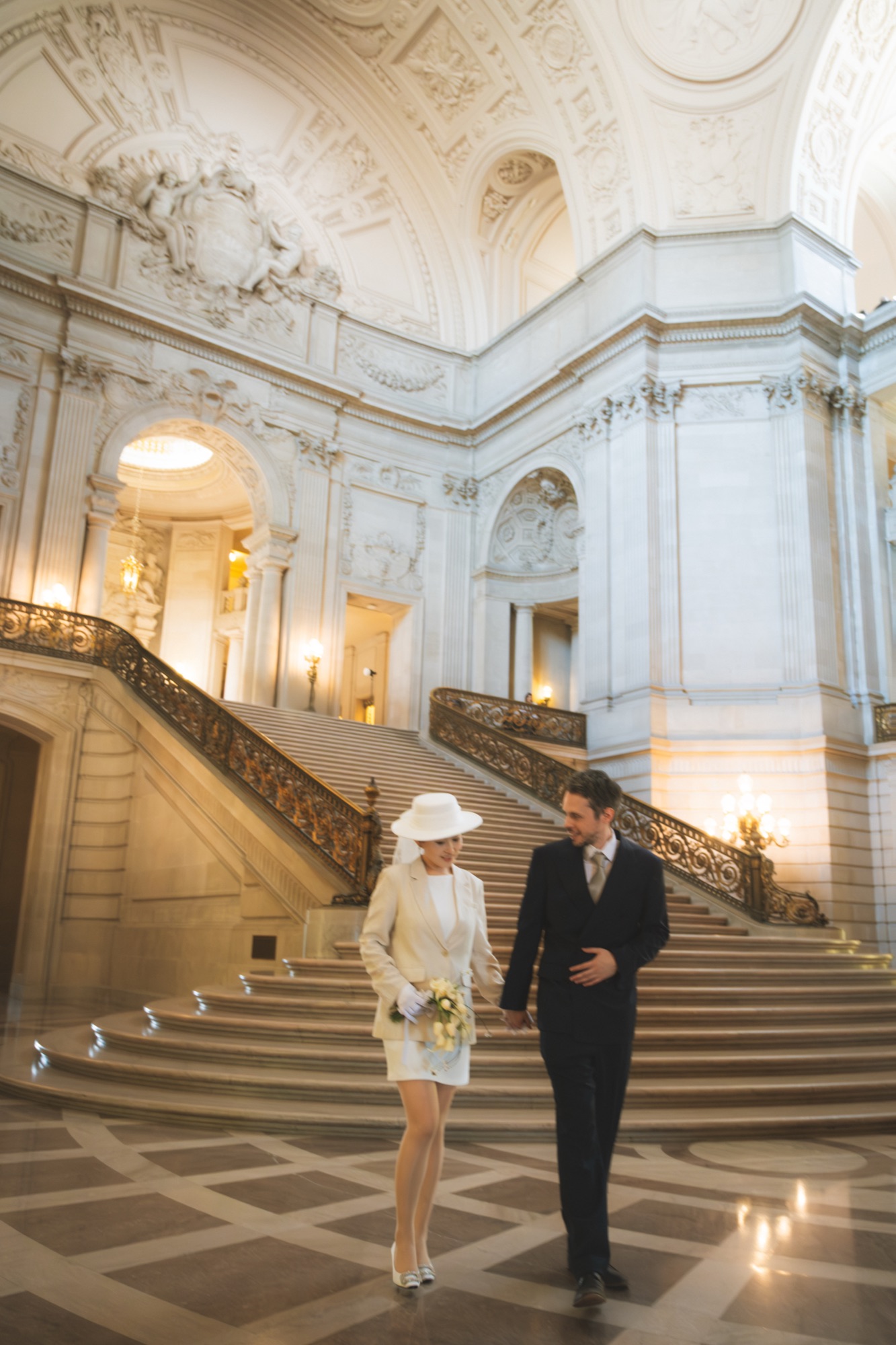 The newlyweds walking down the grand staircase at San Francisco City Hall