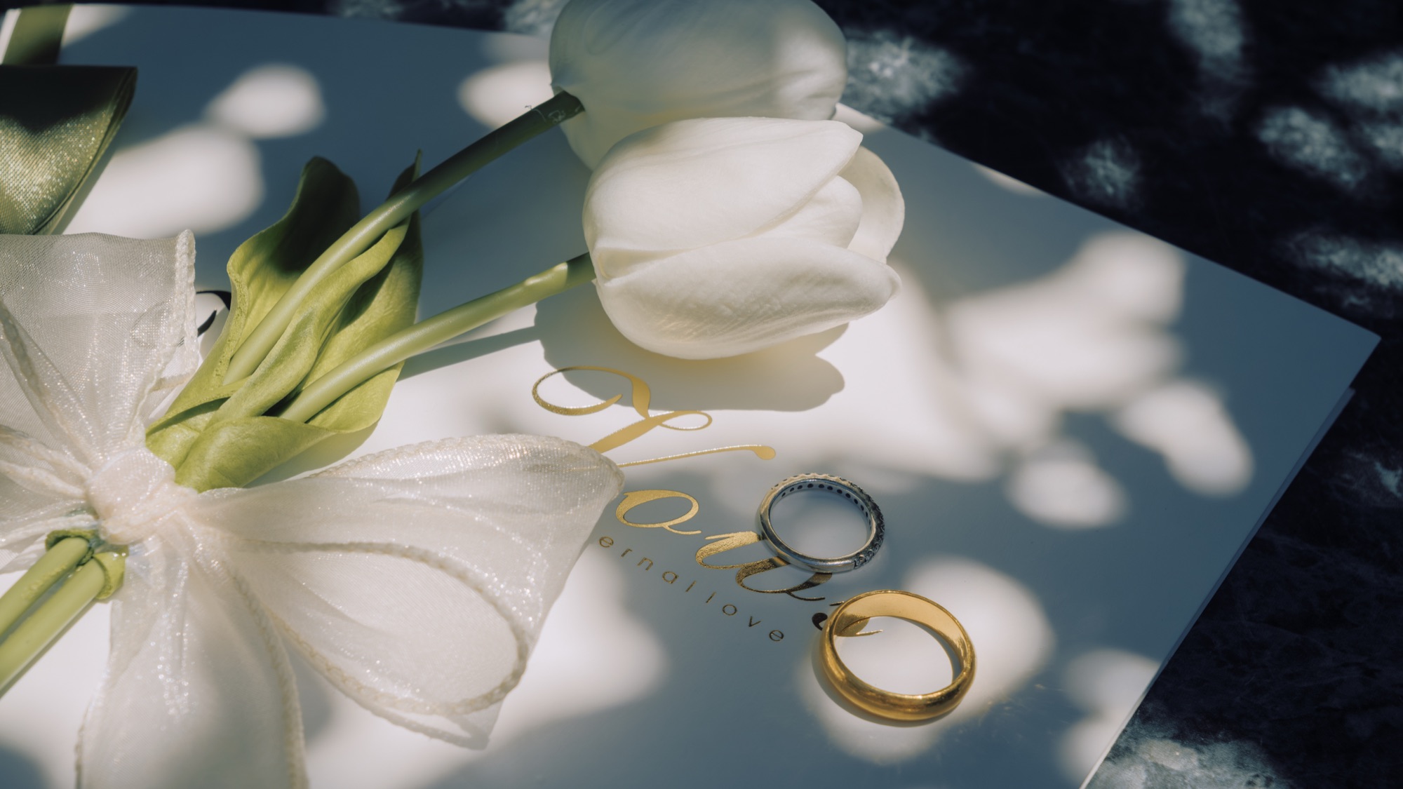 Wedding rings resting beside white flowers