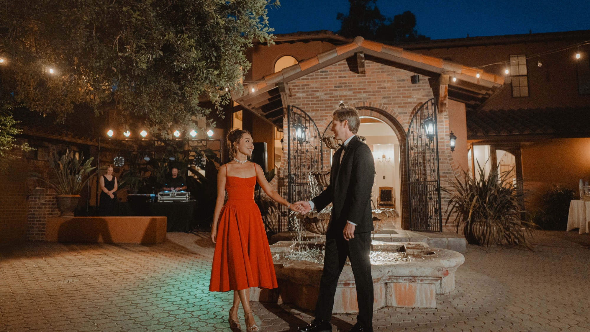 Nicole and Tanner holding hands beside the courtyard fountain at night
